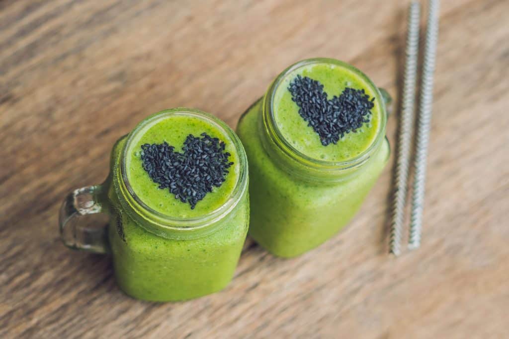vegetable smoothies made with spinach with seeds on top in the shape of a heart