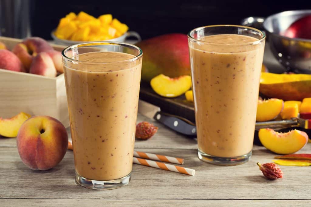 peach mango coconut oil smoothie for weight loss in glasses with ingredients in background