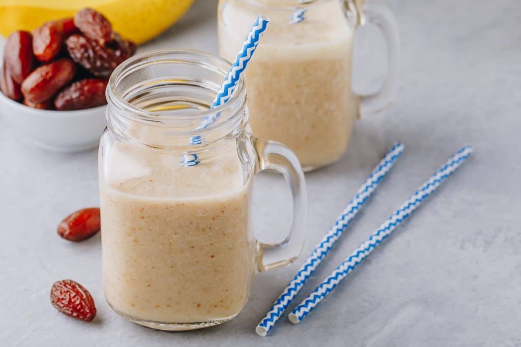 peanut butter date smoothie in glasses on gray background