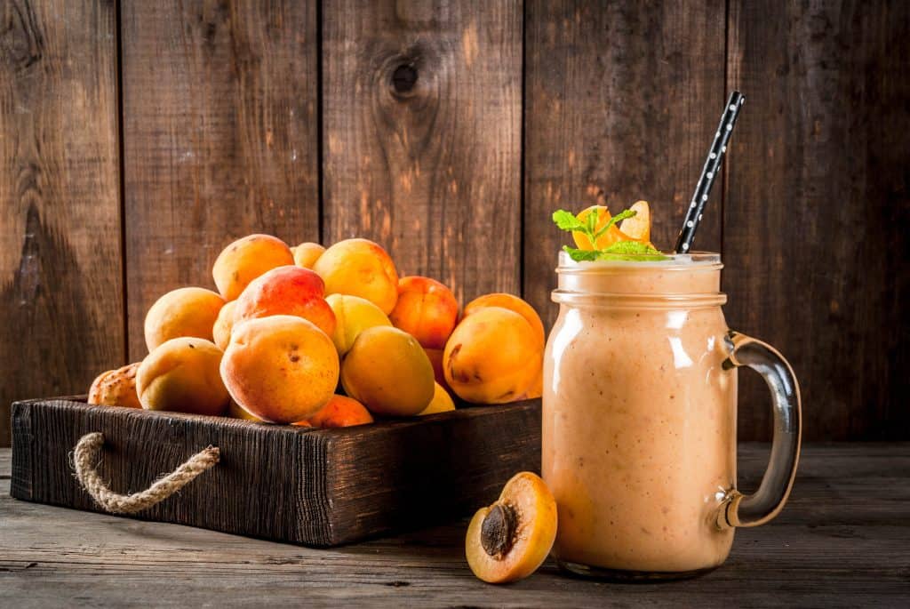 apricot smoothie in mason jar with apricots in background