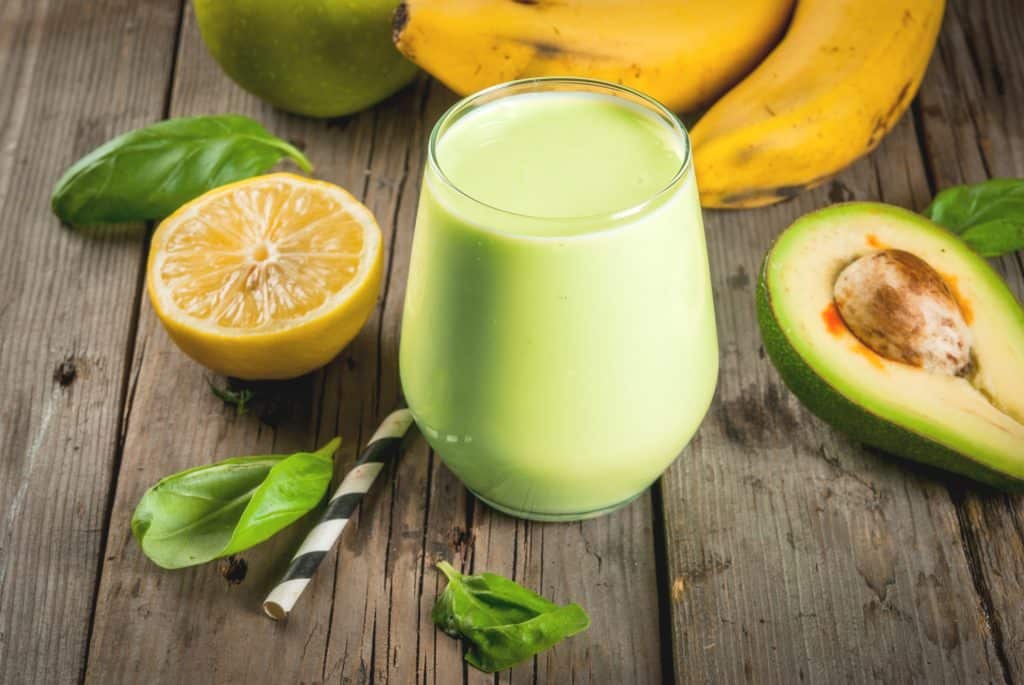 avocado banana smoothie with ingredients in background on wooden table