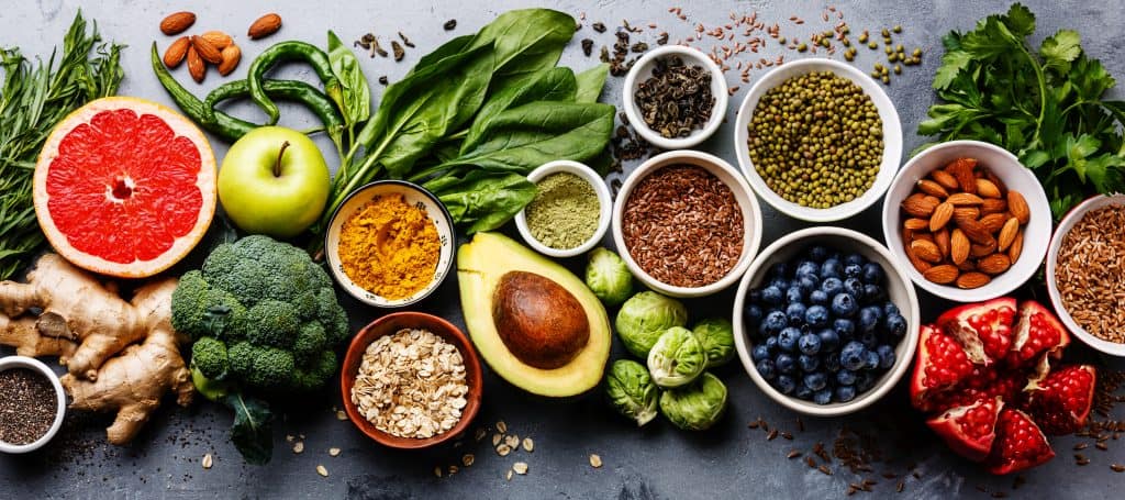 various healthy smoothie ingredients in small bowls on gray background