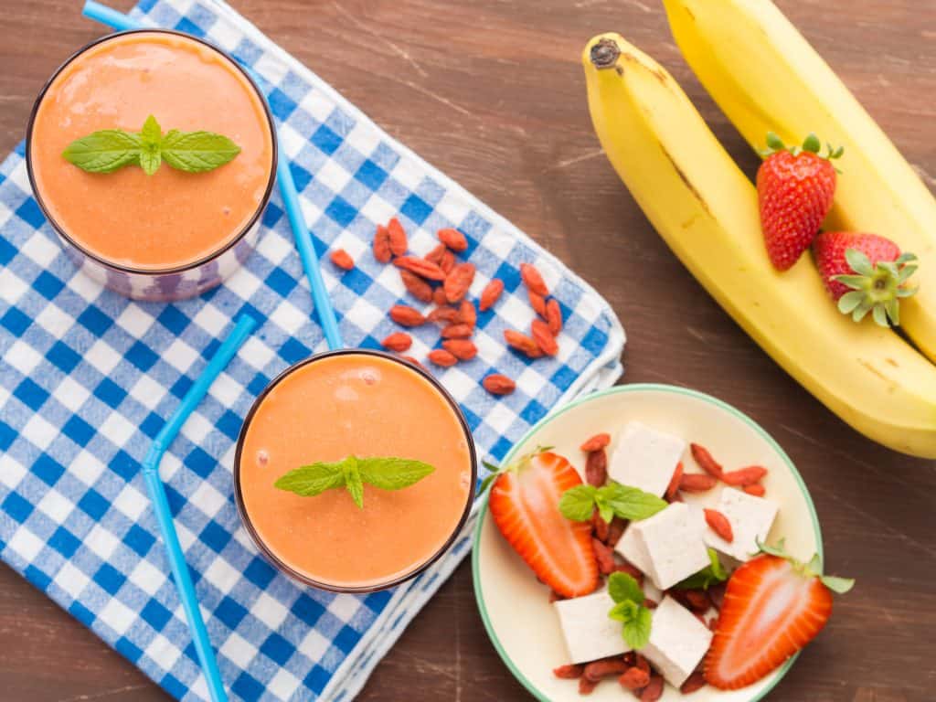 strawberry banana tofu smoothie in glass with ingredients surrounding