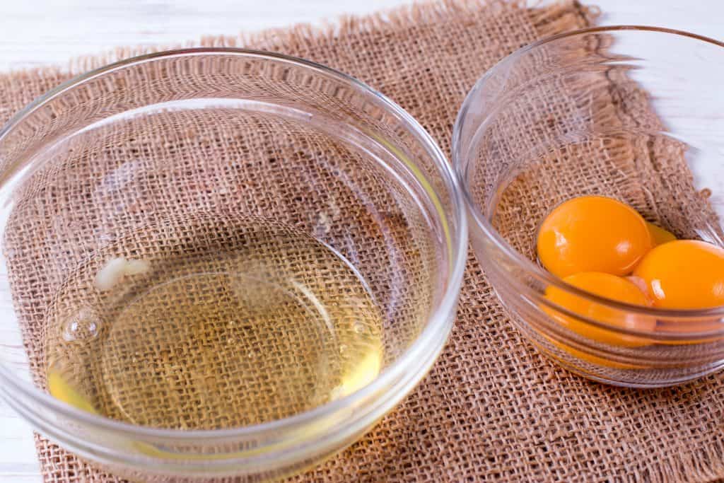 Separated egg white and yolks into two bowls are at background