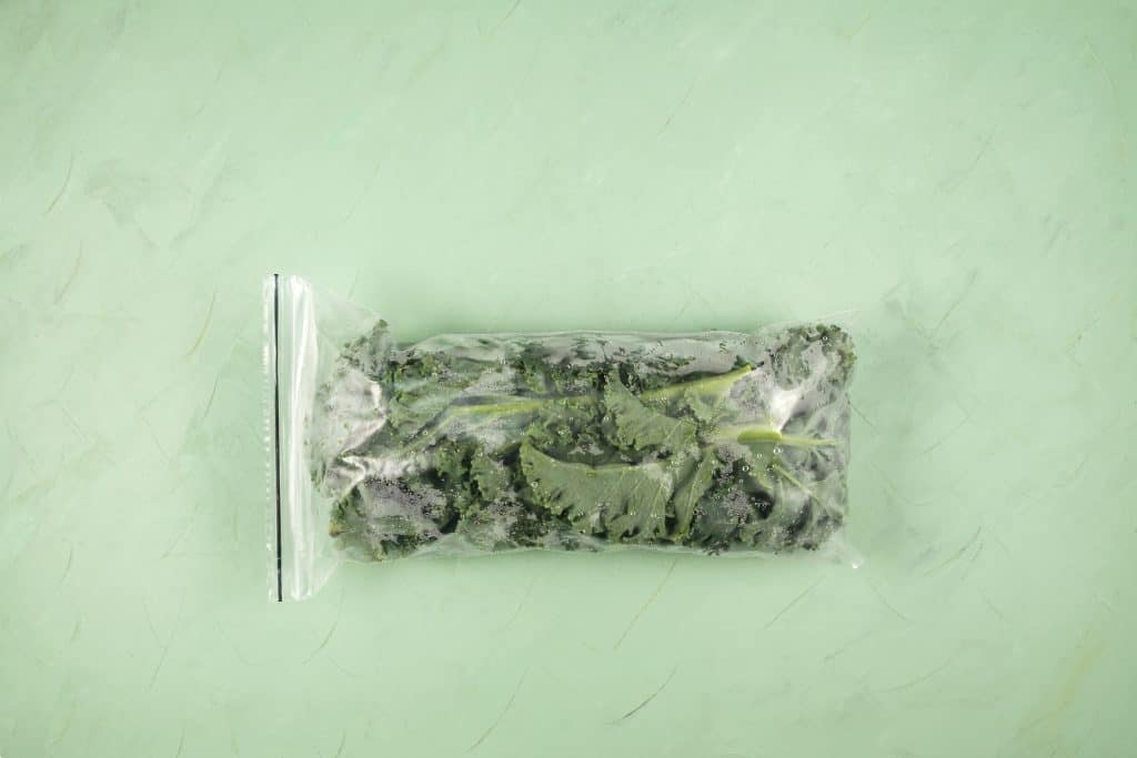 frozen kale in freezer bag on green background