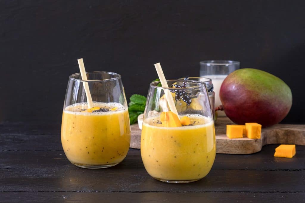 mango chia seed smoothie in glasses with ingredients behind