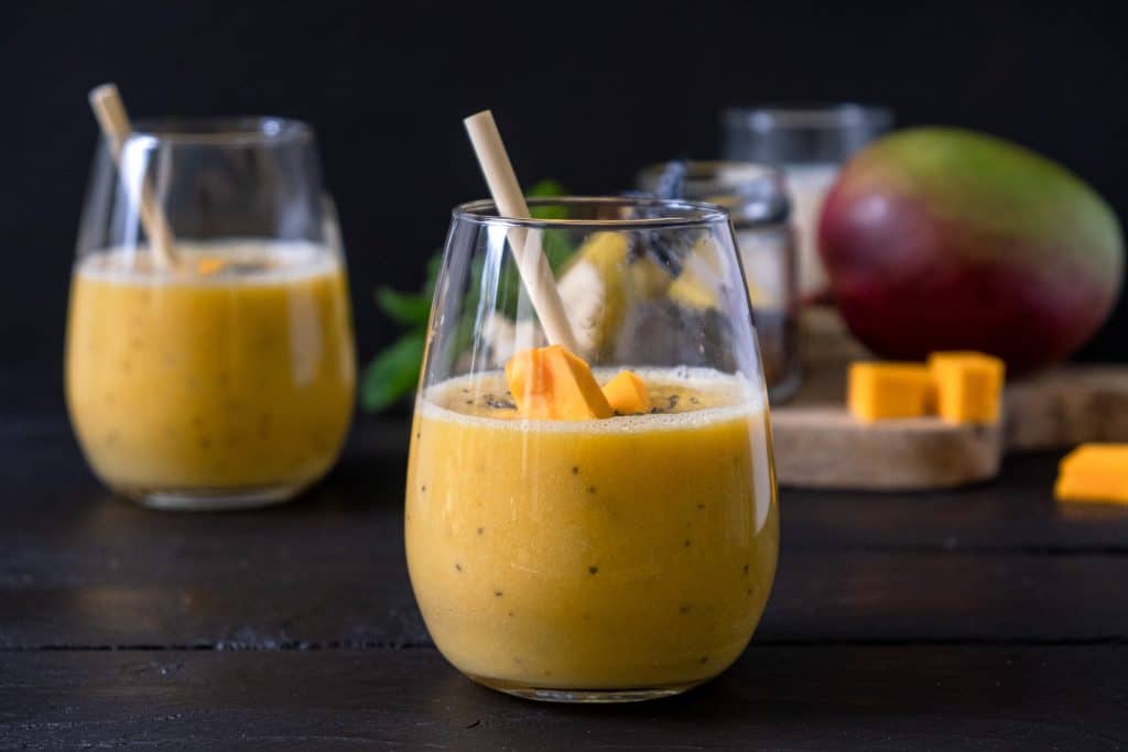 mango chia seed smoothie in glass with ingredients behind