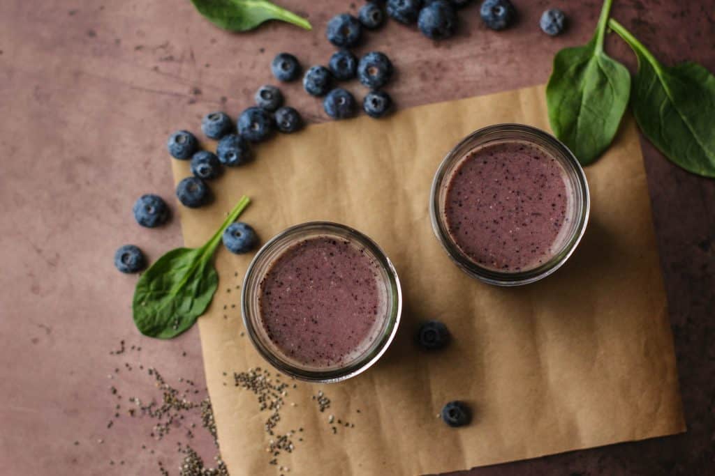 paleo blueberry smoothies in glasses seen from above with blueberries, spinach and chia seeds