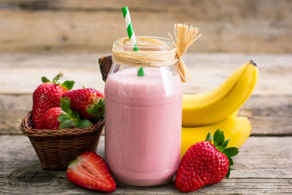 strawberry banana shake in glass on wooden background