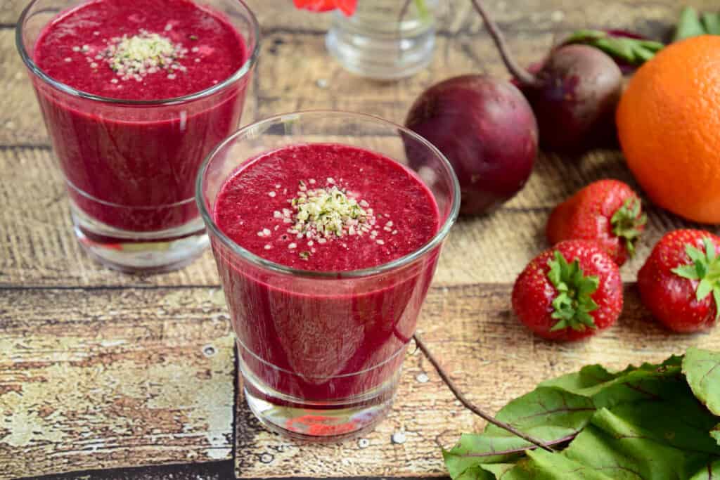 strawberry beet hemp smoothies in glasses with ingredients surrounding