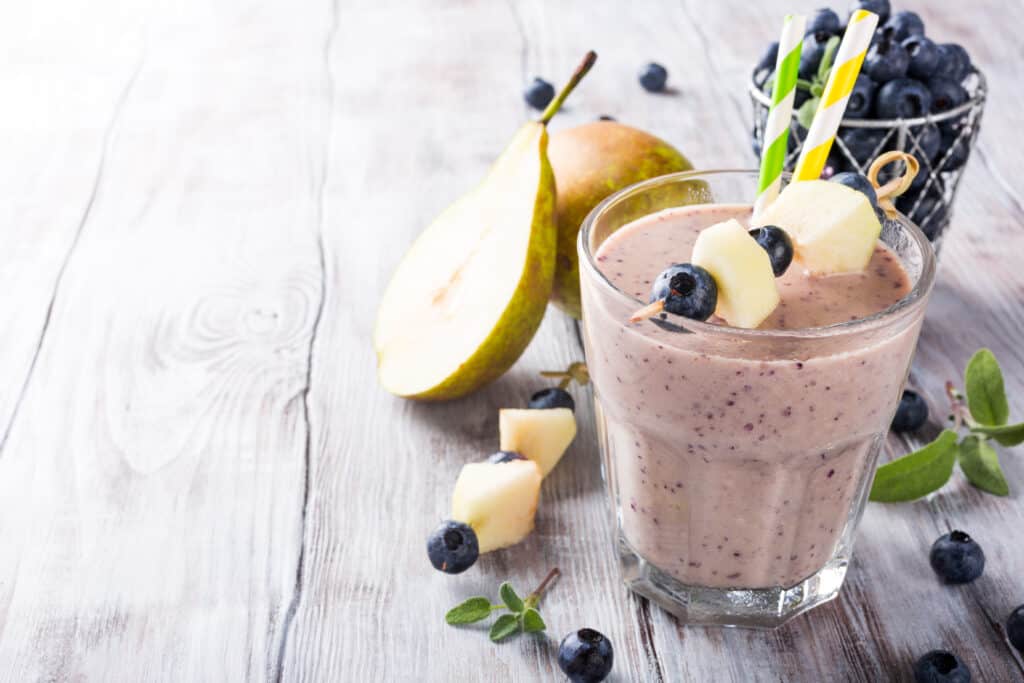 blueberry pear smoothie in glass with blueberries and pears in background