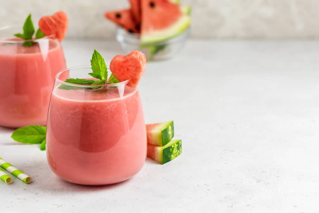 watermelon smoothies in glasses with watermelon slices in background