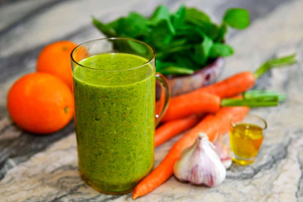 green smoothie made with garlic, carrots, greens and oranges