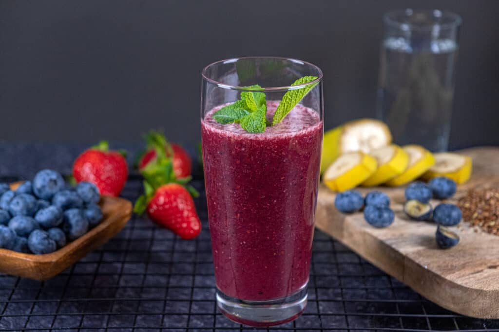 blueberry banana smoothie for weight loss in a glass in front of smoothie ingredients