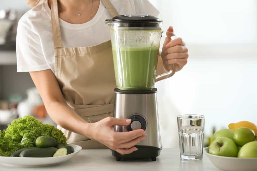 close up of woman blending a green smoothie