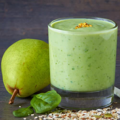 kale spinach and pear smoothie in glass on dark background