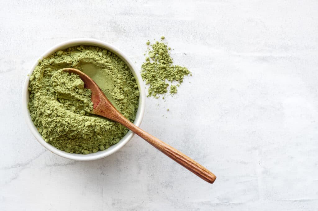 matcha powder in small bowl with wooden spoon