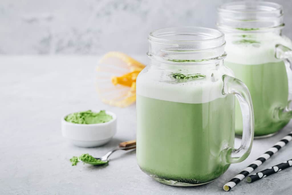 matcha smoothies in glasses with matcha powder in small bowl
