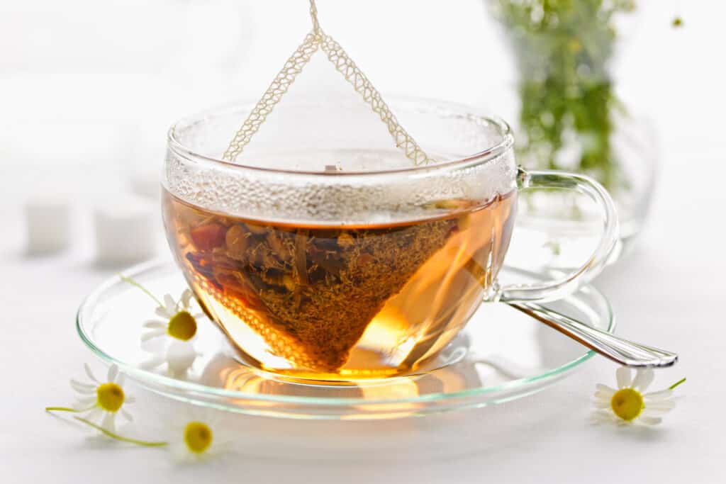 Glass teacup with soothing herbal tea in silk bag