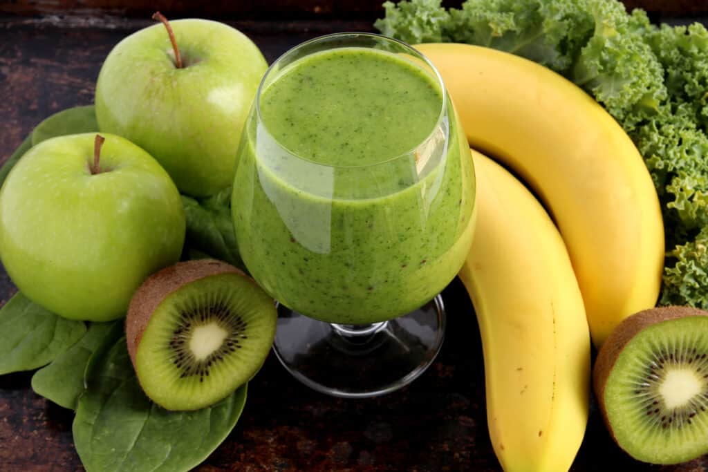 refreshing glass of our green apple weight loss smoothie with ingredients surrounding