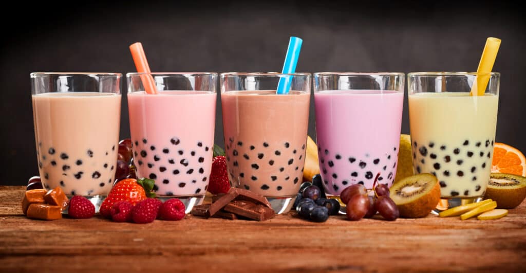 Row of fresh boba shakes on wooden background. 