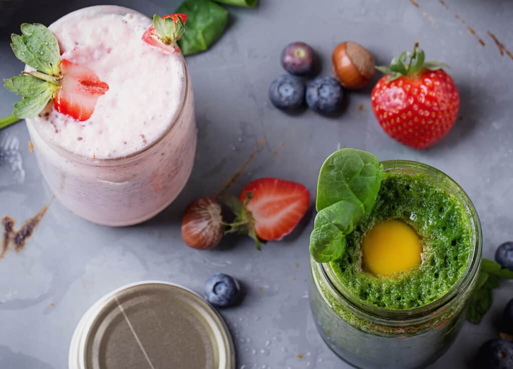 Green and Strawberry smoothie with berries, egg yolk and spinach leaves