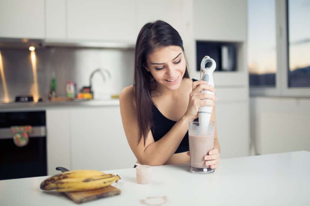 woman using an immersion blender to blend a smoothie
